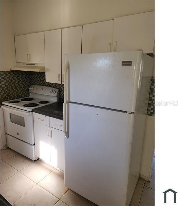 kitchen featuring tasteful backsplash, white appliances, white cabinetry, and light tile patterned floors