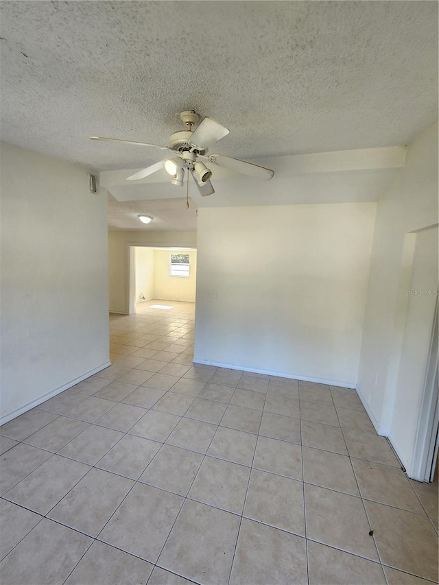 tiled empty room with ceiling fan and a textured ceiling