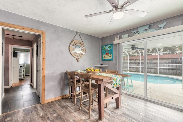 dining space featuring wood-type flooring, a textured ceiling, and ceiling fan