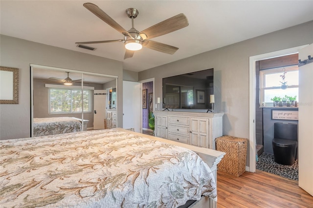 bedroom featuring light hardwood / wood-style floors, a closet, multiple windows, and ceiling fan