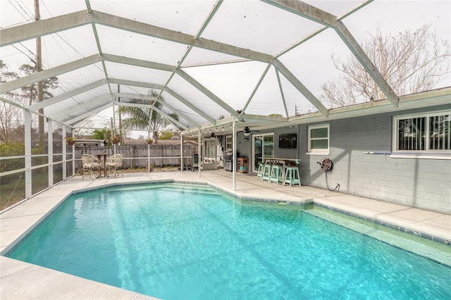 view of pool with glass enclosure, a patio area, and an outdoor bar