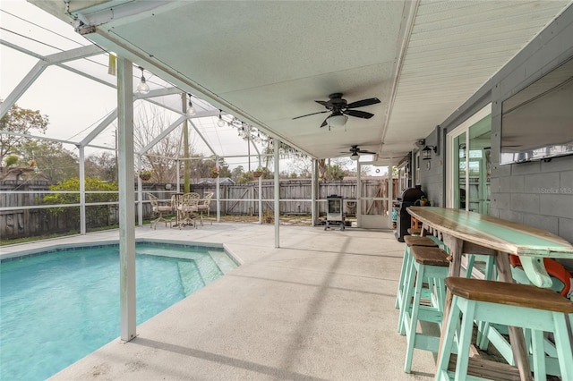 view of swimming pool featuring glass enclosure, ceiling fan, a patio area, and grilling area