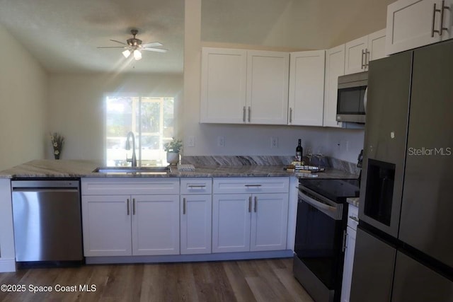 kitchen with kitchen peninsula, sink, white cabinetry, stone counters, and stainless steel appliances