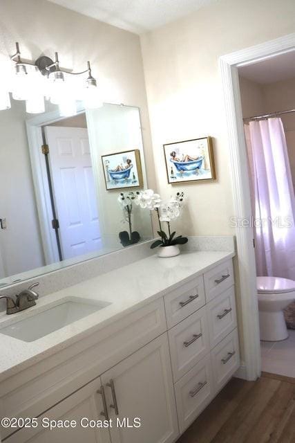 bathroom with hardwood / wood-style flooring, toilet, and vanity