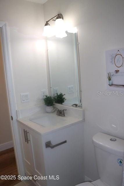 bathroom with hardwood / wood-style flooring, toilet, and vanity