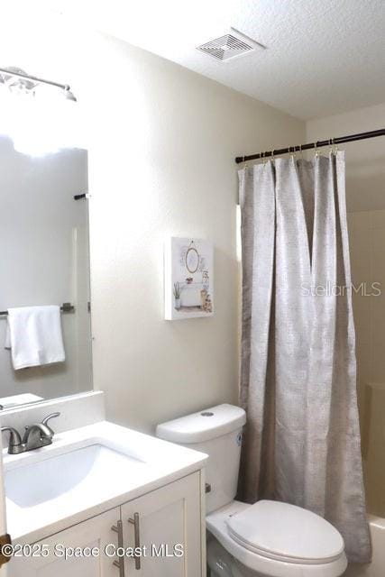 full bathroom with shower / bath combo with shower curtain, a textured ceiling, toilet, and vanity