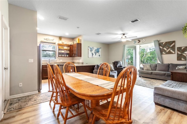 dining room with ceiling fan, light hardwood / wood-style flooring, and a textured ceiling