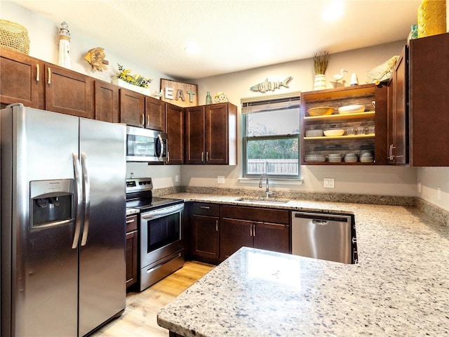 kitchen with sink, dark brown cabinets, light wood-type flooring, stainless steel appliances, and light stone counters