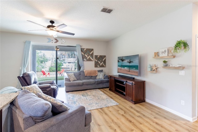 living room featuring a textured ceiling, light hardwood / wood-style flooring, and ceiling fan