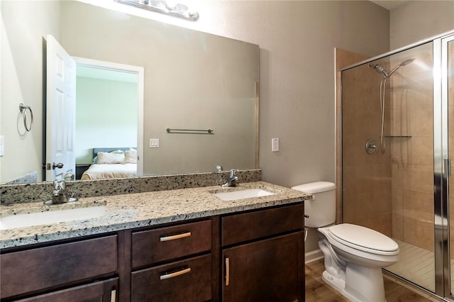 bathroom featuring wood-type flooring, a shower with door, toilet, and vanity