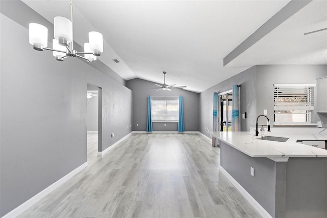 kitchen with ceiling fan with notable chandelier, decorative light fixtures, sink, light hardwood / wood-style floors, and kitchen peninsula