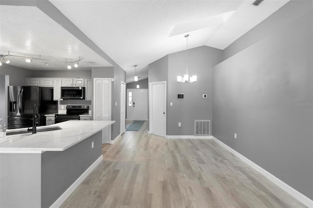 kitchen with vaulted ceiling, white cabinets, light wood-type flooring, and black appliances