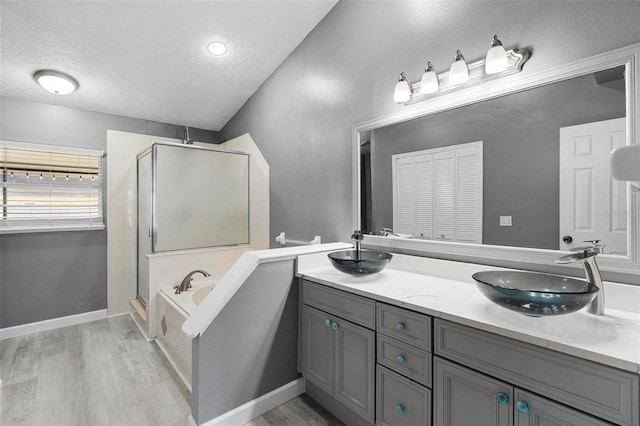 bathroom with a textured ceiling, wood-type flooring, and separate shower and tub