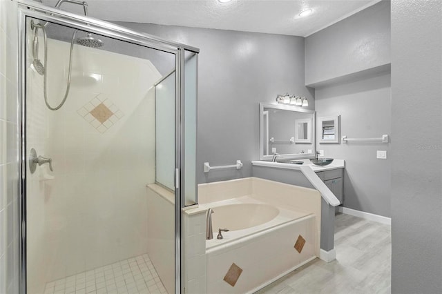 bathroom featuring vanity, a textured ceiling, wood-type flooring, and separate shower and tub