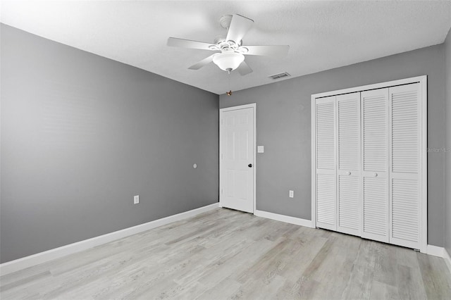 unfurnished bedroom with ceiling fan, light hardwood / wood-style floors, a closet, and a textured ceiling