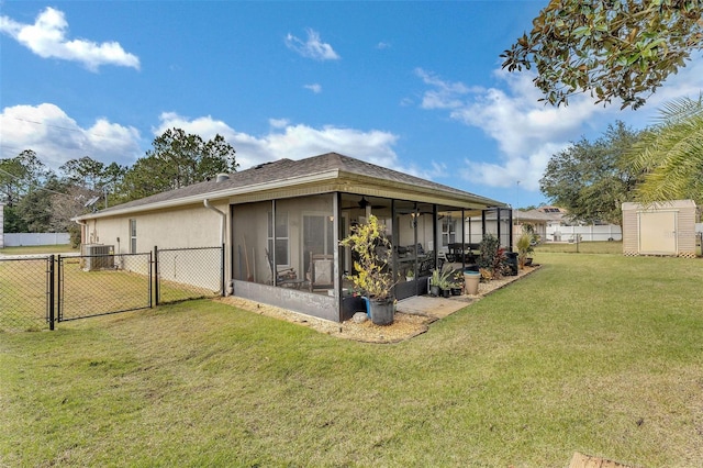 rear view of property featuring cooling unit, a lawn, and a sunroom