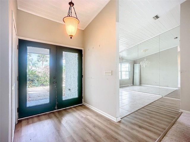 foyer entrance featuring light hardwood / wood-style flooring, wooden ceiling, and french doors