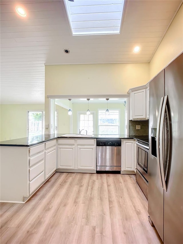 kitchen with stainless steel appliances, white cabinetry, hanging light fixtures, and decorative backsplash