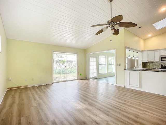 unfurnished living room with wood ceiling, ceiling fan, a skylight, and light hardwood / wood-style flooring