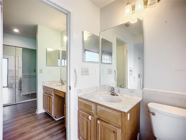 bathroom featuring vanity, wood-type flooring, tile walls, and toilet