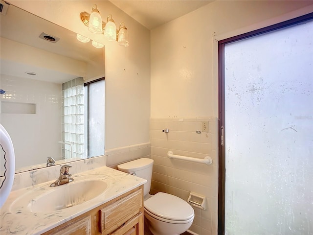 bathroom featuring vanity, tile walls, and toilet