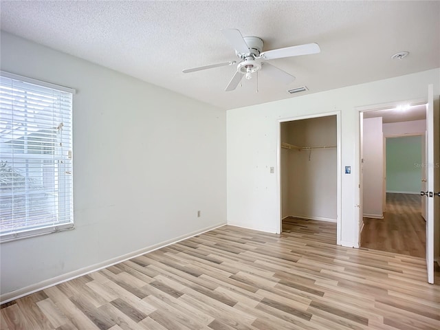 unfurnished bedroom featuring a textured ceiling, light hardwood / wood-style floors, a closet, and ceiling fan