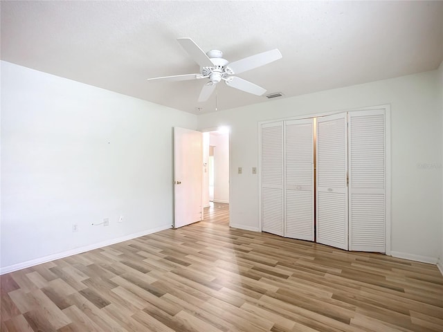 unfurnished bedroom featuring ceiling fan, light hardwood / wood-style floors, and a closet