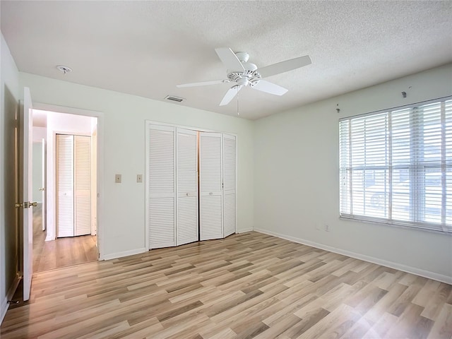 unfurnished bedroom featuring a textured ceiling, ceiling fan, and light wood-type flooring