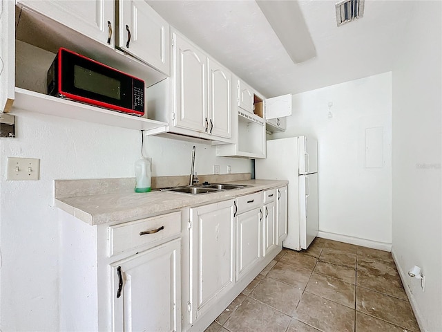 kitchen featuring sink, light tile patterned floors, white cabinets, and white fridge