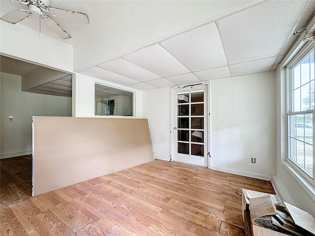 spare room with ceiling fan, plenty of natural light, light hardwood / wood-style flooring, and a drop ceiling