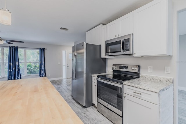 kitchen with pendant lighting, white cabinetry, stainless steel appliances, and light hardwood / wood-style floors