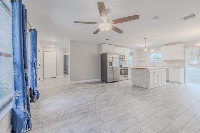 kitchen with pendant lighting, sink, appliances with stainless steel finishes, a center island, and white cabinets