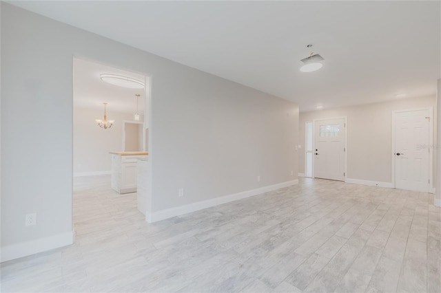 empty room with an inviting chandelier and light wood-type flooring