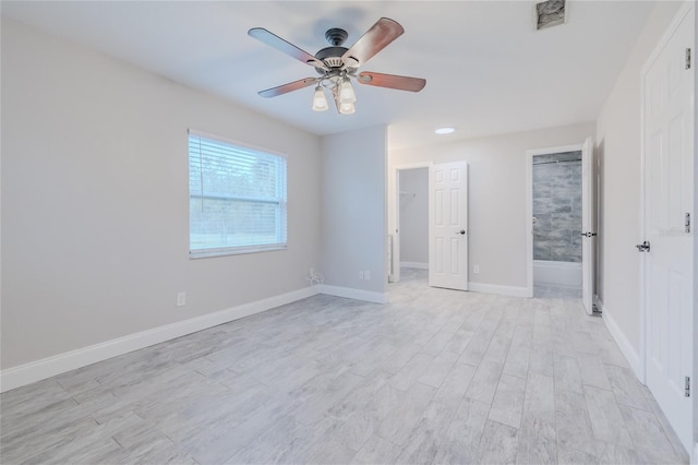 unfurnished bedroom with ensuite bathroom, a spacious closet, ceiling fan, light wood-type flooring, and a closet