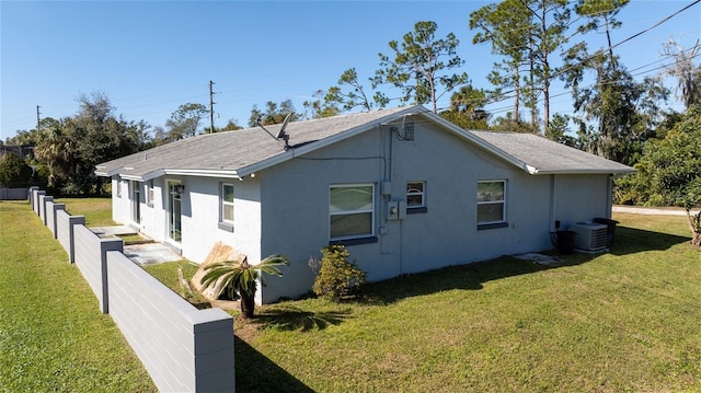 view of side of property featuring central AC unit and a lawn