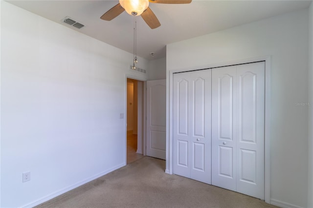 unfurnished bedroom with light colored carpet, ceiling fan, and a closet