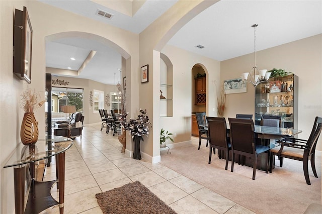 carpeted dining area featuring a notable chandelier and a raised ceiling