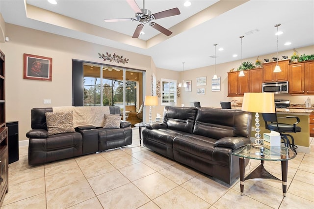 tiled living room featuring a raised ceiling and ceiling fan