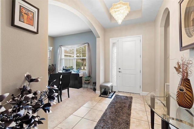 carpeted entrance foyer with a chandelier and a raised ceiling