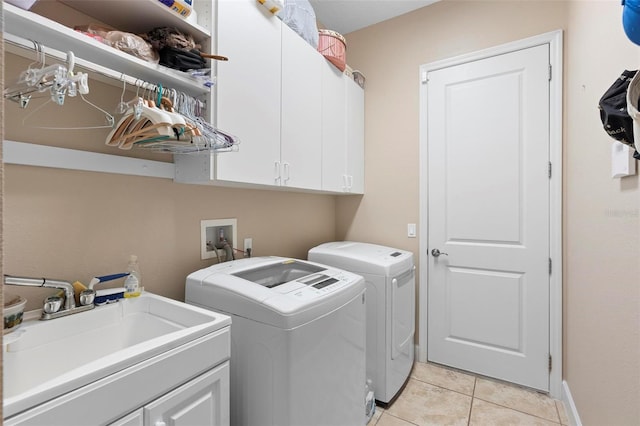 clothes washing area featuring cabinets, washing machine and dryer, sink, and light tile patterned flooring