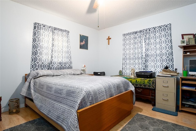 bedroom with light wood-type flooring, a textured ceiling, and ceiling fan