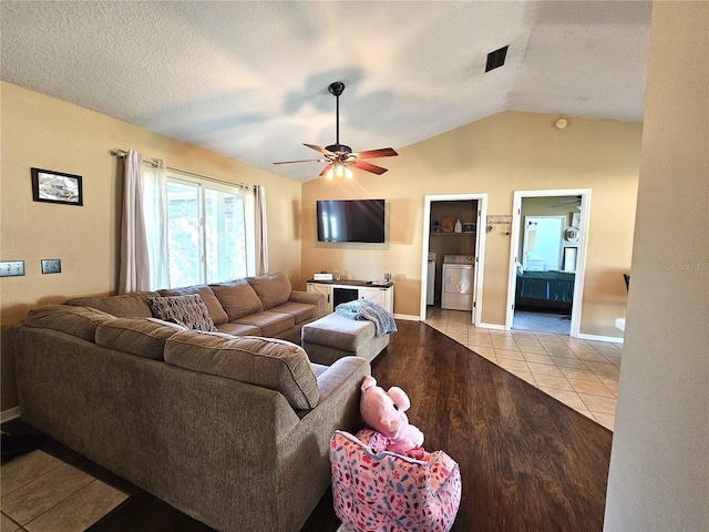 living room featuring ceiling fan, independent washer and dryer, vaulted ceiling, and light tile patterned floors