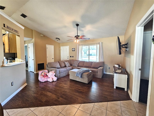 tiled living room featuring ceiling fan, vaulted ceiling, and a textured ceiling