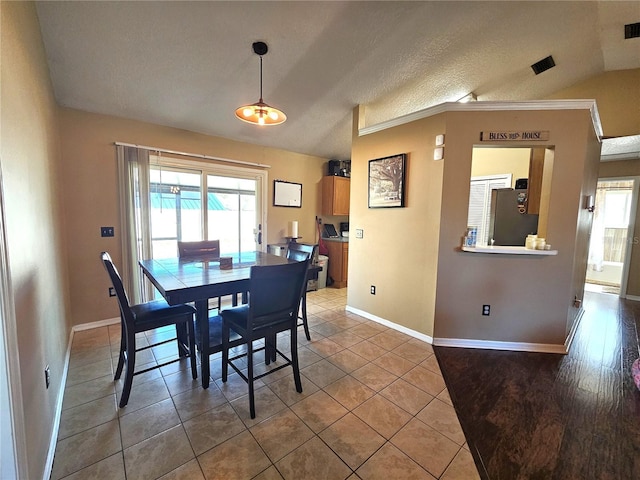 tiled dining area with vaulted ceiling and a textured ceiling