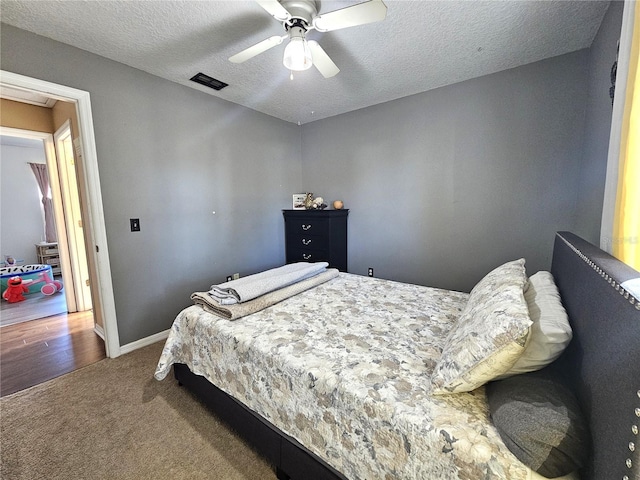 bedroom with a textured ceiling, ceiling fan, and carpet