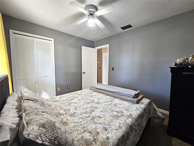 bedroom with ceiling fan, carpet floors, a closet, and a textured ceiling