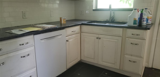 kitchen with dark tile patterned flooring, a sink, white cabinets, tasteful backsplash, and dark countertops