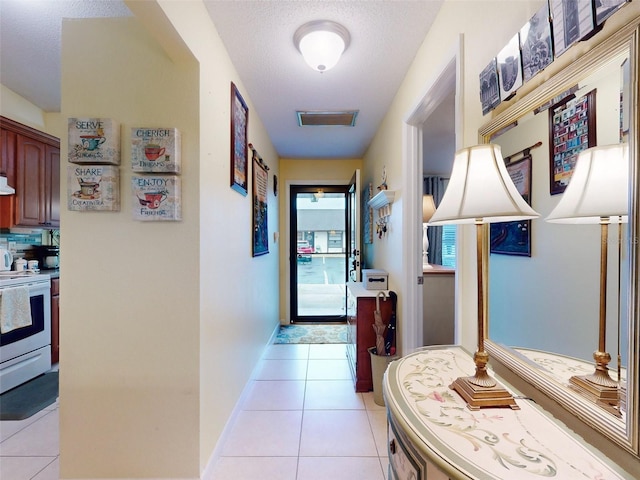 corridor with a textured ceiling and light tile patterned floors