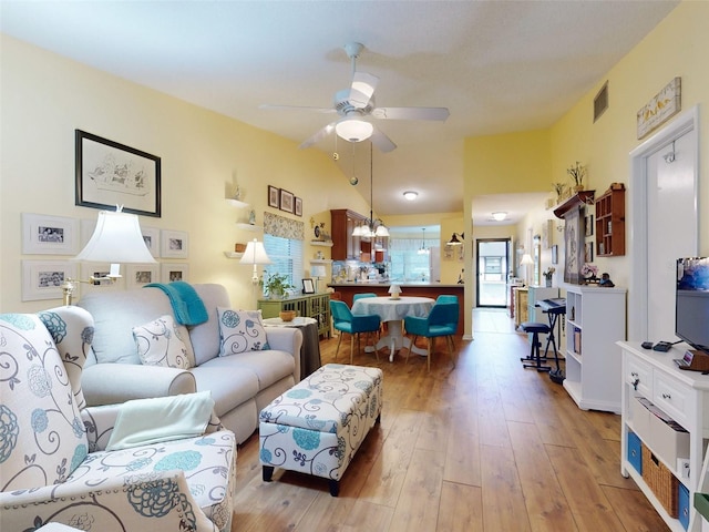 living room featuring ceiling fan with notable chandelier, lofted ceiling, and light hardwood / wood-style floors