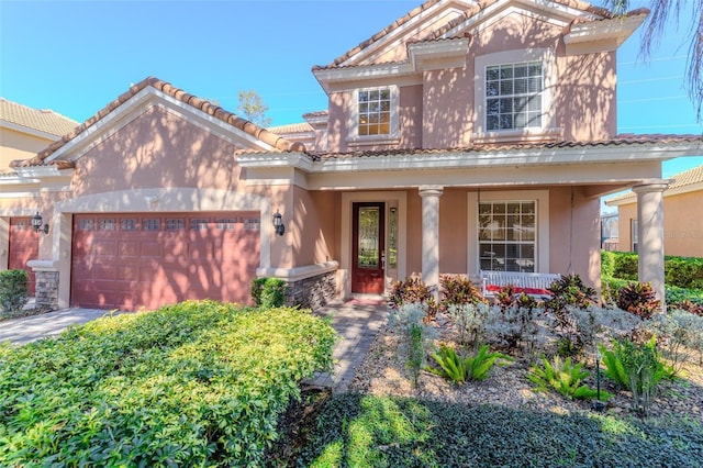 view of front of house featuring a tile roof, stucco siding, covered porch, an attached garage, and driveway